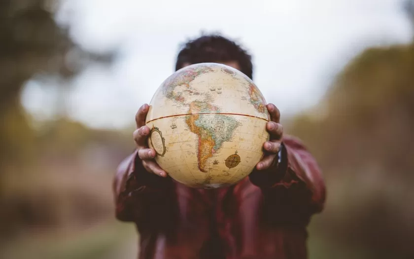 Closeup shot of a male wearing a leather jacket holding a globe in front of him